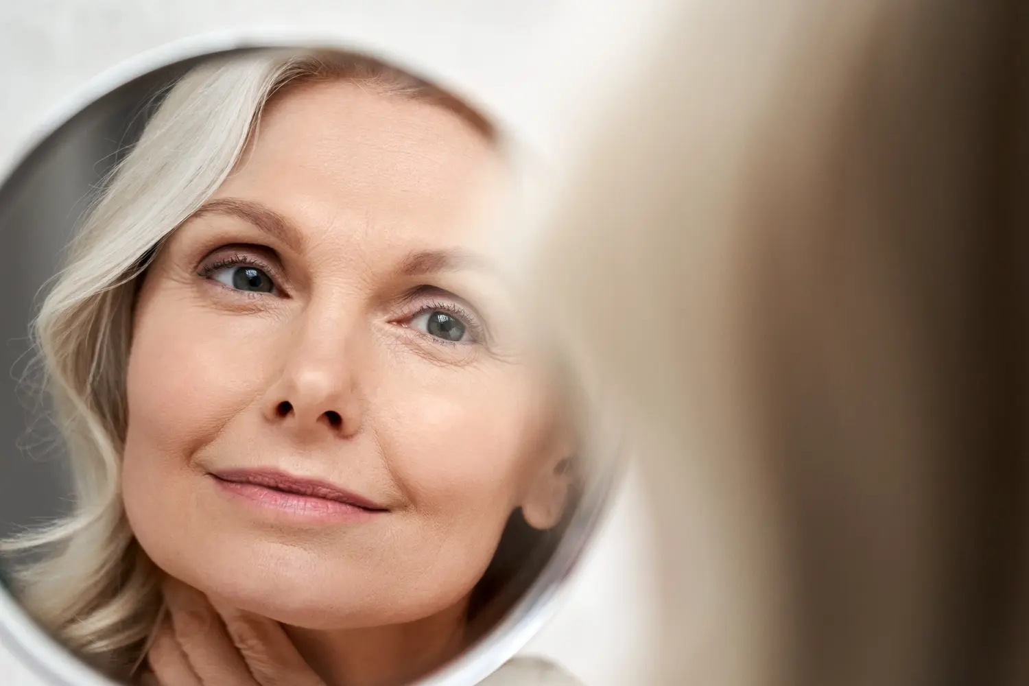 elegant woman with gray hair looking in mirror utc